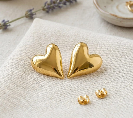 Détail du volume et du poli miroir des boucles d'oreilles cœurs dorées sur toile naturelle.