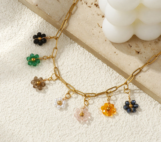 Gros plan d'une femme portant le collier fleurs multicolores avec un pull beige.