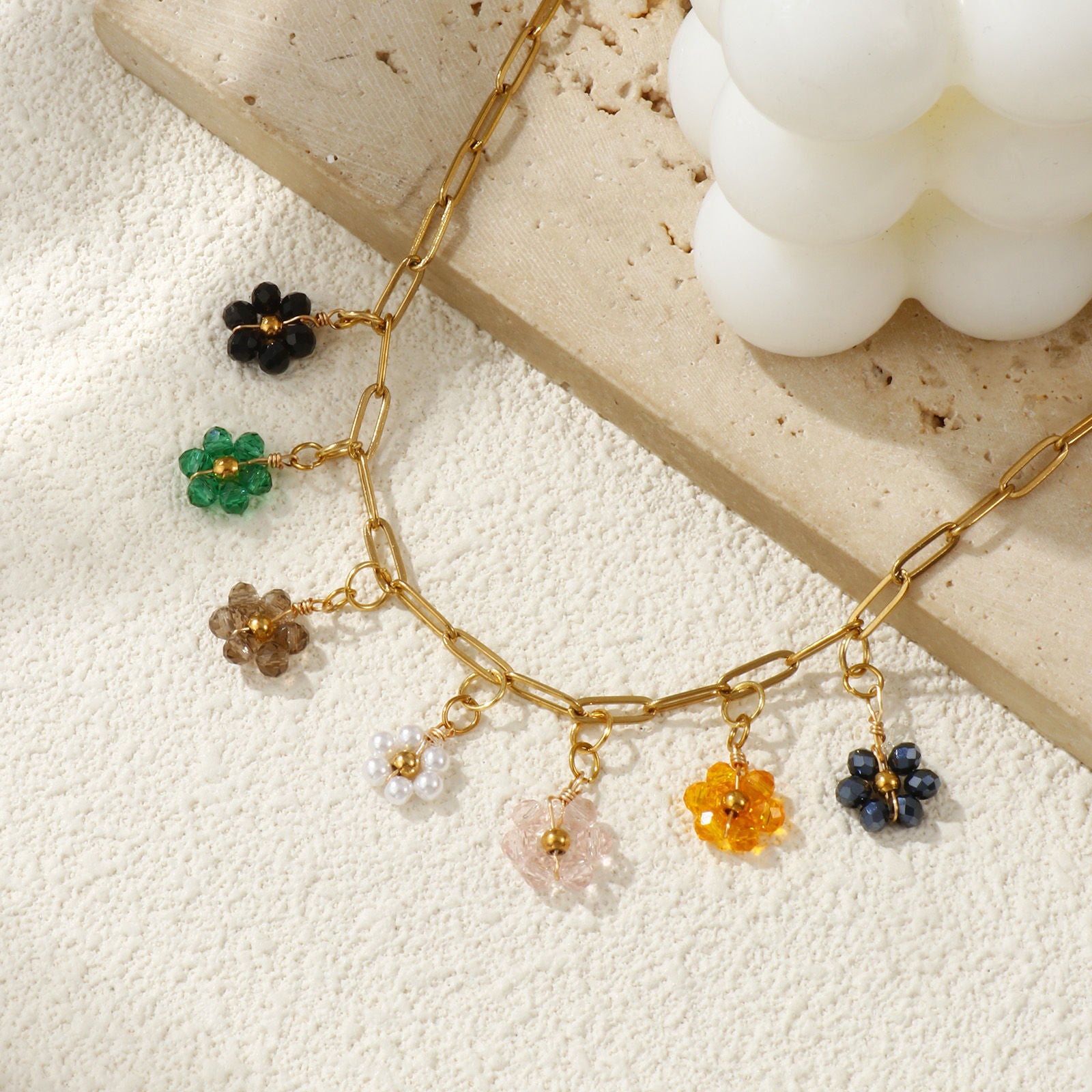 Gros plan d'une femme portant le collier fleurs multicolores avec un pull beige.